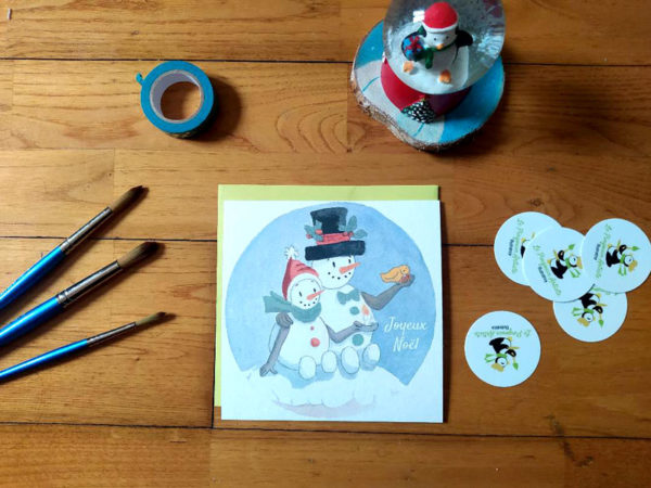 Carte de Noël avec deux bonshommes de neige et un petit oiseau.